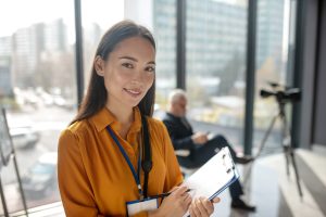 Work dome. Young beaming pretty asian reporter looking contented while making notes