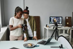 Portrait of two female photographers looking at photos in camera while working at photo studio, copy space